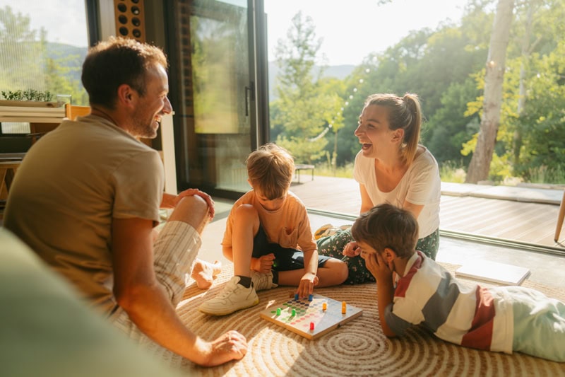 Family sitting inside in the sun together enjoying air purification system for better indoor air quality (IAQ) in their home.
