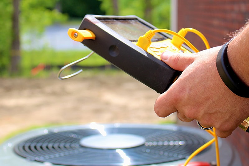 3 Tips to Prevent AC Breakdown During a Heat Wave. A technician fixing an air conditioner.