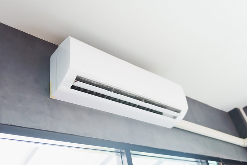 Discover the Benefits of Ductless Mini Splits in Northwest Oregon. Cool air conditioner swing system on wall in room.