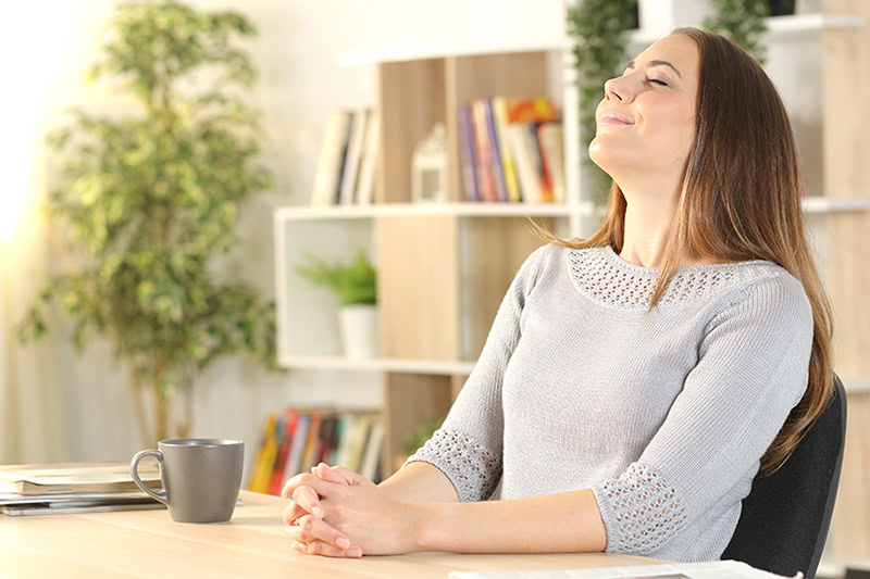 3 Tips to Improve Indoor Air During Allergy Season in Oregon. Photo of a young woman enjoying clean air in her home office.