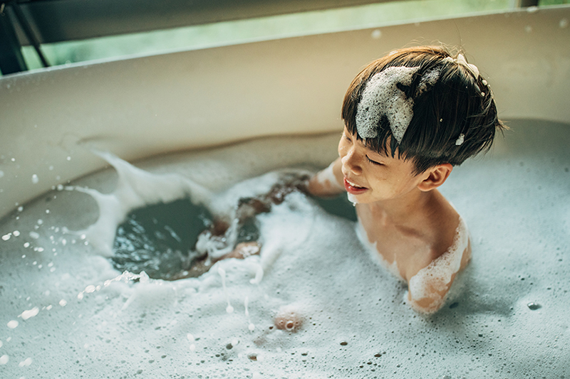 What Is a Tankless Water Heater? Photo of a child in a bathtub full of suds.